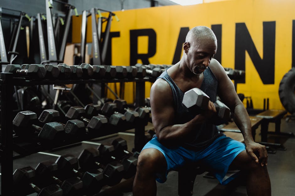 Adult man performing dumbbell curls in a modern gym, emphasizing strength and fitness.