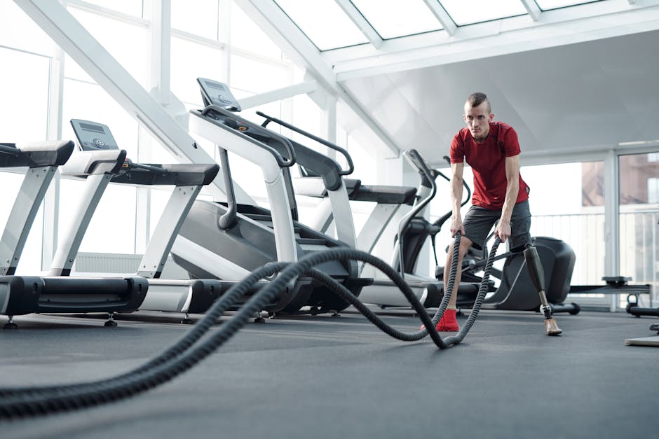 Young man with prosthetic leg working out in a modern gym with battle ropes, showcasing strength and determination.