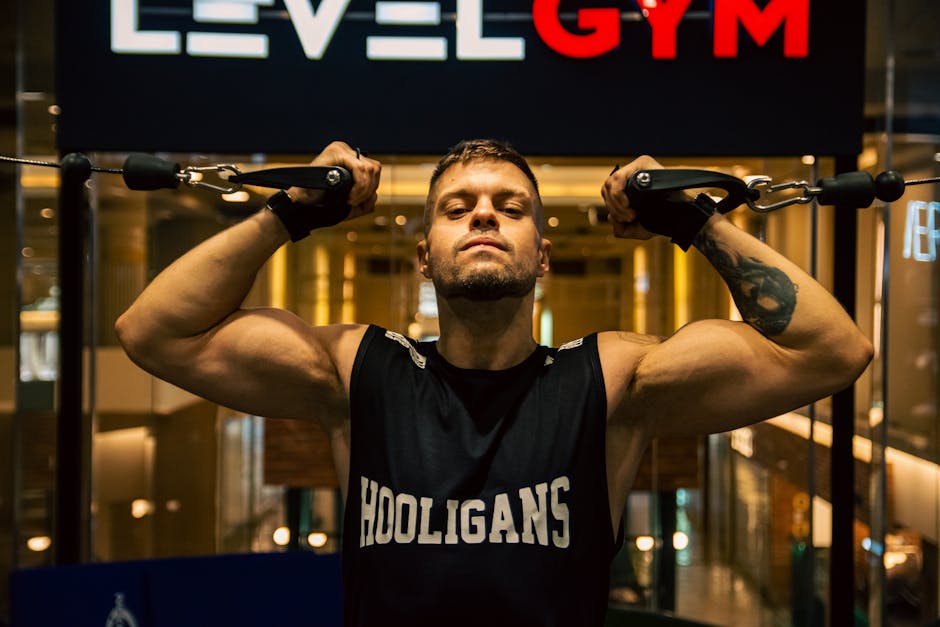 A muscular man working out at a modern indoor gym, demonstrating strength training.